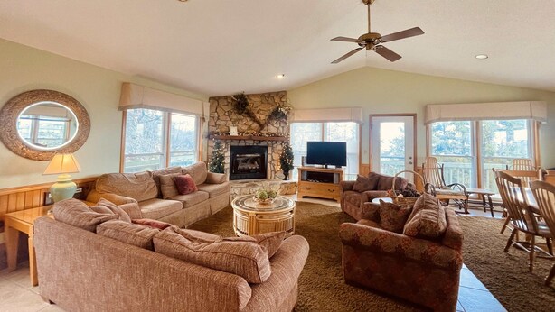 A spacious living room with a fireplace, a ceiling fan, and a dining area with chairs and a table. - TM-2  Cox Retreat Amazing 6-Bedroom Hot Tub (Beech Mountain)