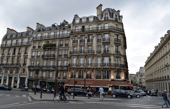 Un edificio de varios pisos con balcones, comercios y un paso de peatones.