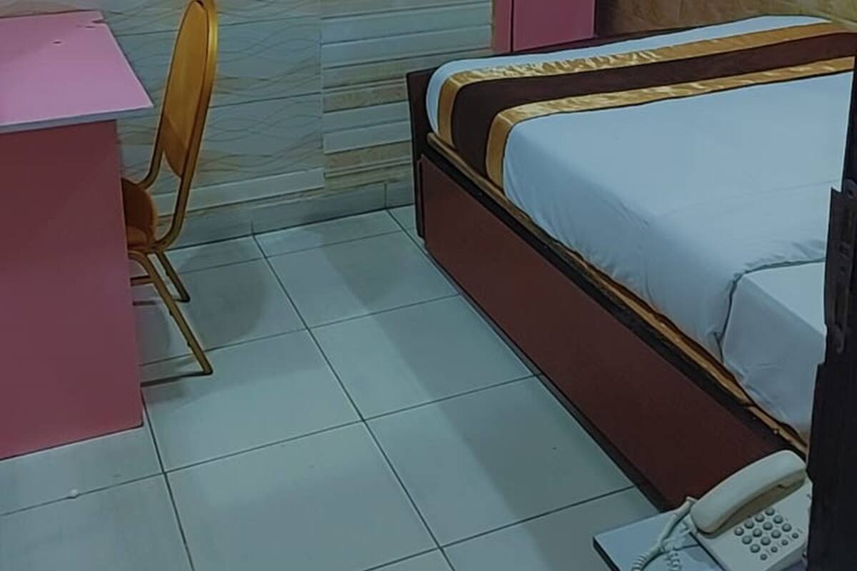 Ein Schlafzimmer mit einem Bett, einem Schreibtisch, einem Stuhl, einem an der Wand befestigten Fernseher und einem Kleiderschrank.