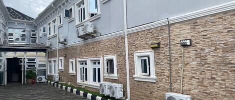 A building with multiple windows, a stone facade, and air conditioning units.