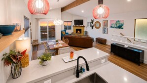 A modern kitchen with a central island, a dining area with a view, and a living room with a fireplace.
