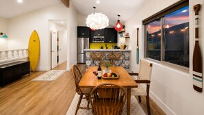 A modern kitchen with black cabinets, a stainless steel refrigerator, and a yellow surfboard leaning against the wall.