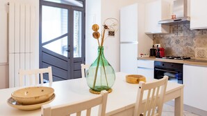 A modern kitchen with white cabinetry, a large window, and a dining table with chairs.