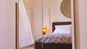 A bedroom with a bed, a bedside table with a lamp, and a decorative wall piece.