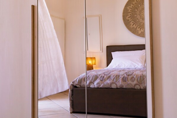 A bedroom with a bed, a bedside table with a lamp, and a decorative wall piece.