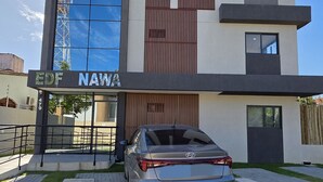 Ένα σύγχρονο κτίριο με γυάλινη πρόσοψη, ένα αυτοκίνητο Hyundai σταθμευμένο μπροστά και μια πινακίδα με την επιγραφή «EDF NAWA».