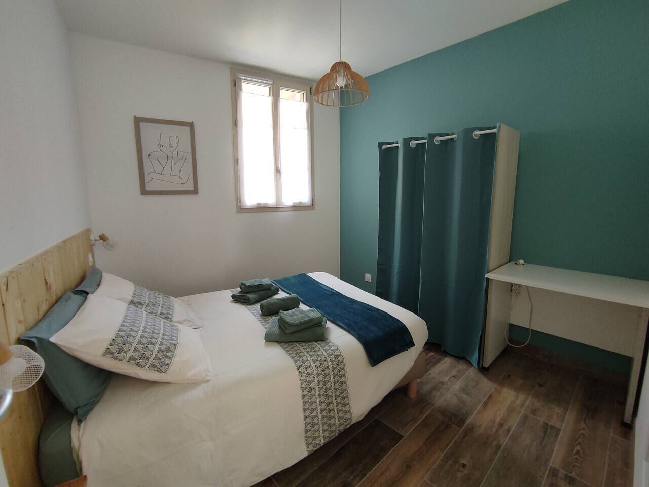 A bedroom with a bed, a desk, a window, and curtains.