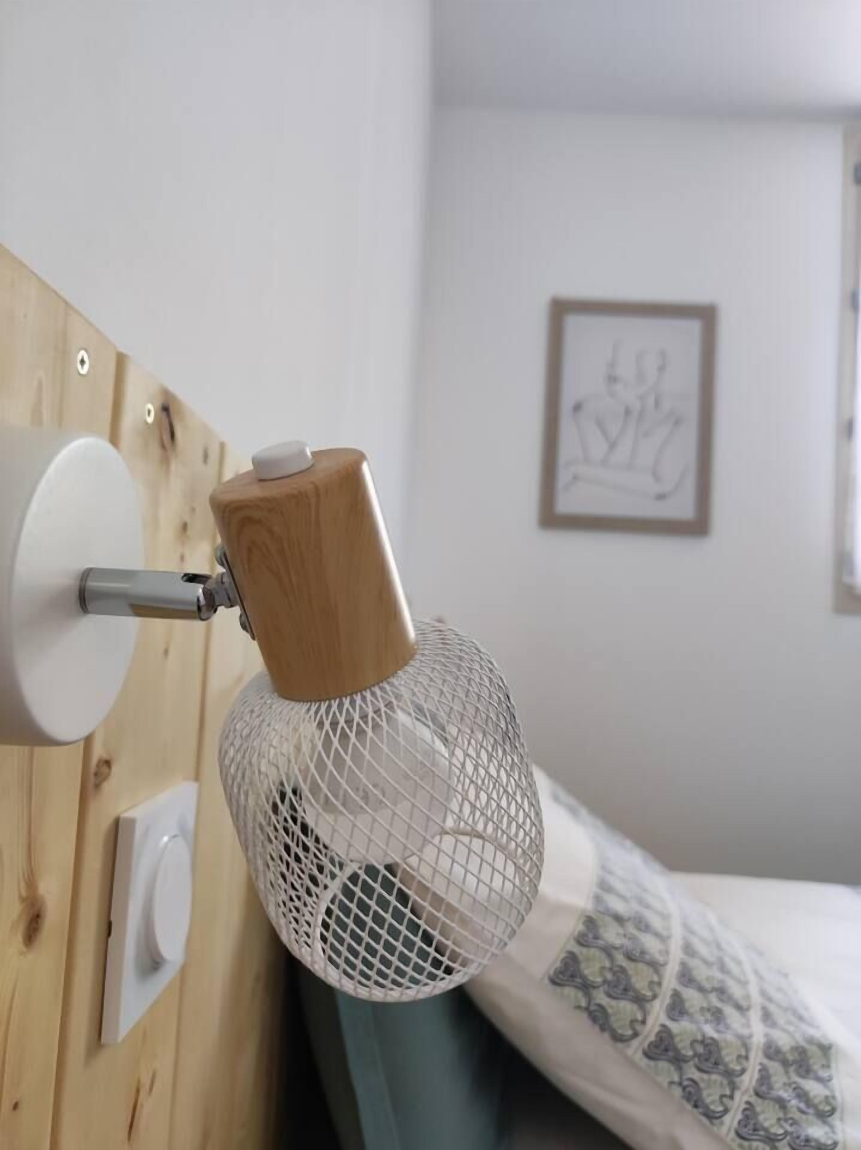 Ett rum med en sänggavel i trä, en vit vägg och en inramad tavla.