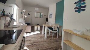 Una cocina moderna con comedor, piso de madera y una pared de acento color verde azulado.