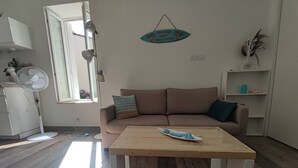 Una sala de estar con un sofá, una mesa de centro de madera y una mesita auxiliar.