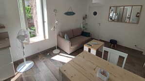 Una sala moderna con un sofá, una mesa de comedor y un ventilador de pie.