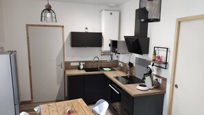 A compact kitchen with a wooden table, black cabinets, and a coffee maker.
