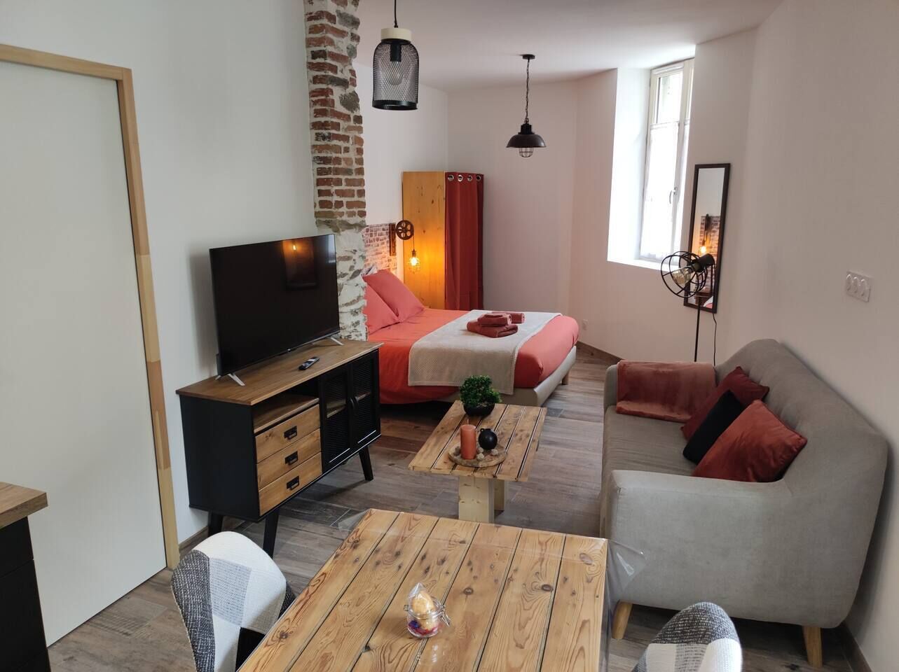 A modern living room with a sofa, a coffee table, a TV, and a bed.