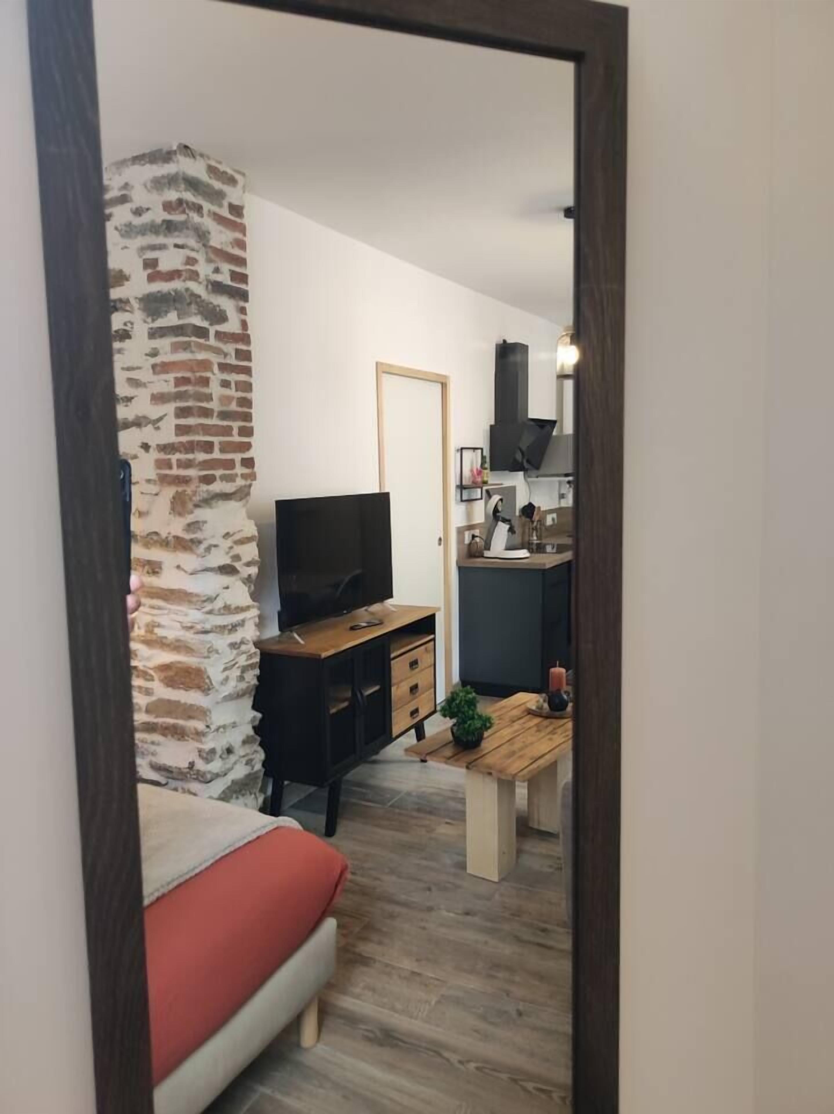 Una sala de estar con televisor, sofá, mesa de centro y pared con diseño de ladrillo.