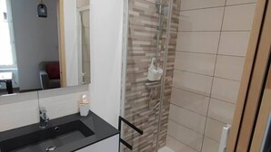 A modern bathroom with a black sink, a mirror, and a glass shower enclosure.