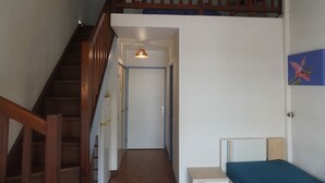En trappa som leder upp till andra våningen, en dörr längst ner i en hall och en säng med en blå madrass.