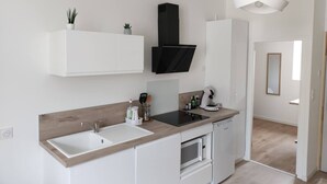 Una cocina moderna con armarios blancos, encimera de madera, campana extractora negra y una lámpara colgante.