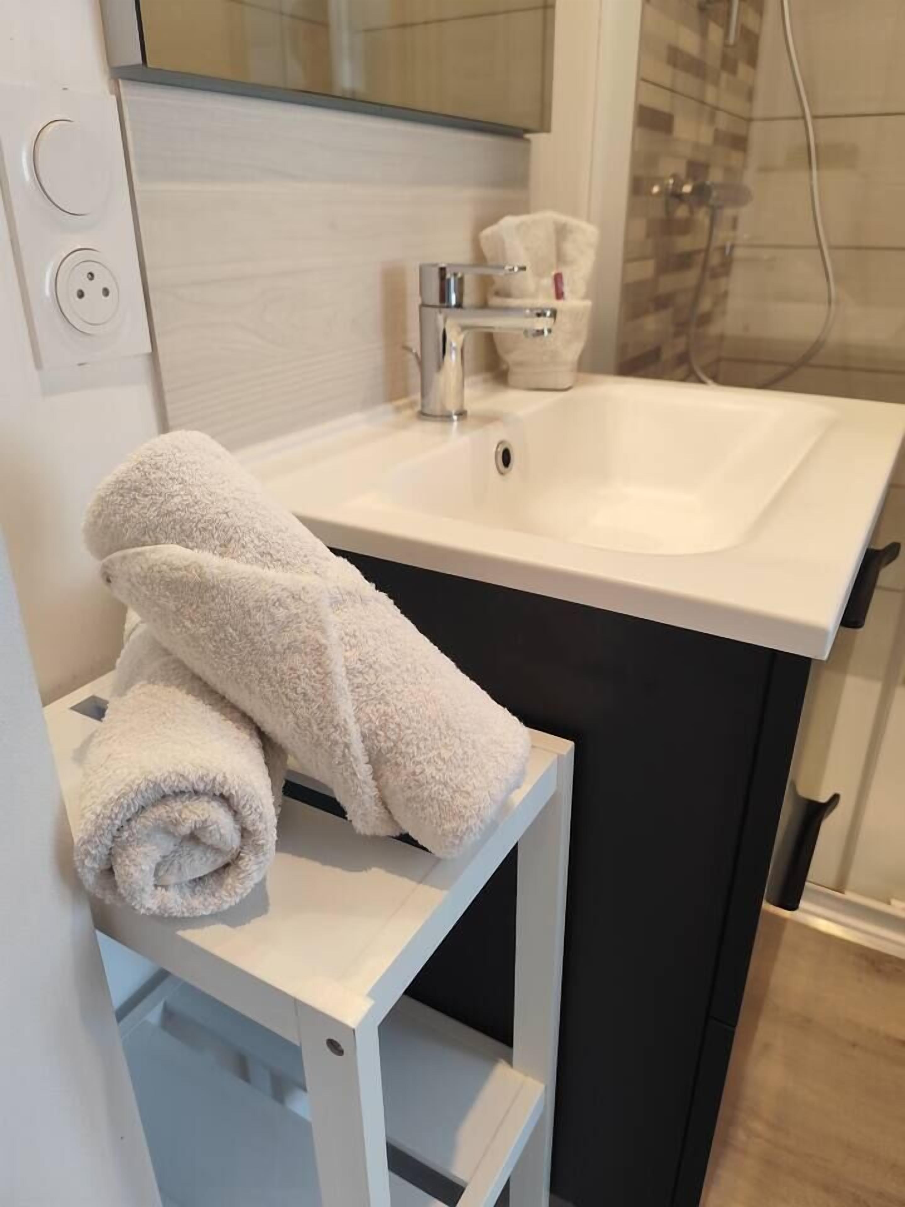 A bathroom with a white sink, a towel rack, and a shower area.