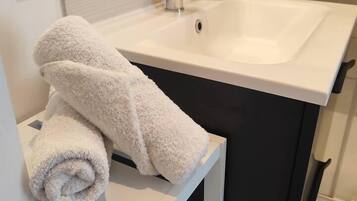 A bathroom with a white sink, a towel rack, and a shower area.