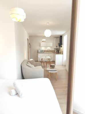 A modern, compact living space with a bed, a sofa, a dining area, and a kitchenette. - Studio Coquet in the center of Beaupréau (Beaupréau-en-Mauges)