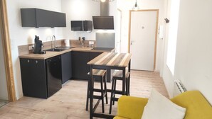 Une cuisine compacte comprenant un coin repas, un canapé et une porte.