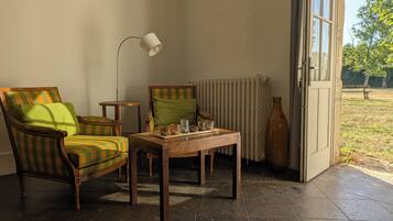 Una habitación con sillones a rayas, una mesita, una lámpara de pie y un radiador.