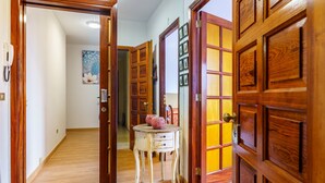 Un pasillo con puertas de madera, una pequeña mesa con adornos y un cuadro en la pared.