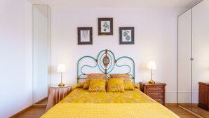 Un dormitorio con una cama, dos mesitas de noche, un aparador y un espejo.