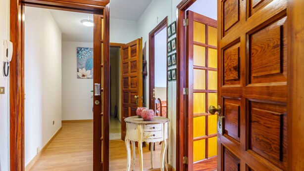 A hallway with wooden doors, a small table with decorative items, and a painting on the wall. - Living Sol - Centric Urban Room 5 (Santa Cruz de Tenerife)