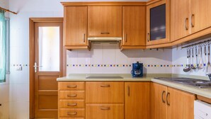 A kitchen with wooden cabinets, a stove, and a coffee maker. - Living Sol - Centric Urban Room 5 (Santa Cruz de Tenerife)