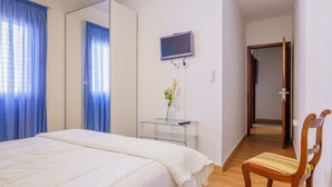 A bedroom with a bed, a TV mounted on the wall, a chair, and a small table with a vase. - Living Sol - Centric Urban Room 5 (Santa Cruz de Tenerife)