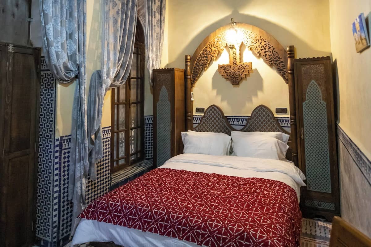 A room with a bed, patterned curtains, and a decorative ceiling light.