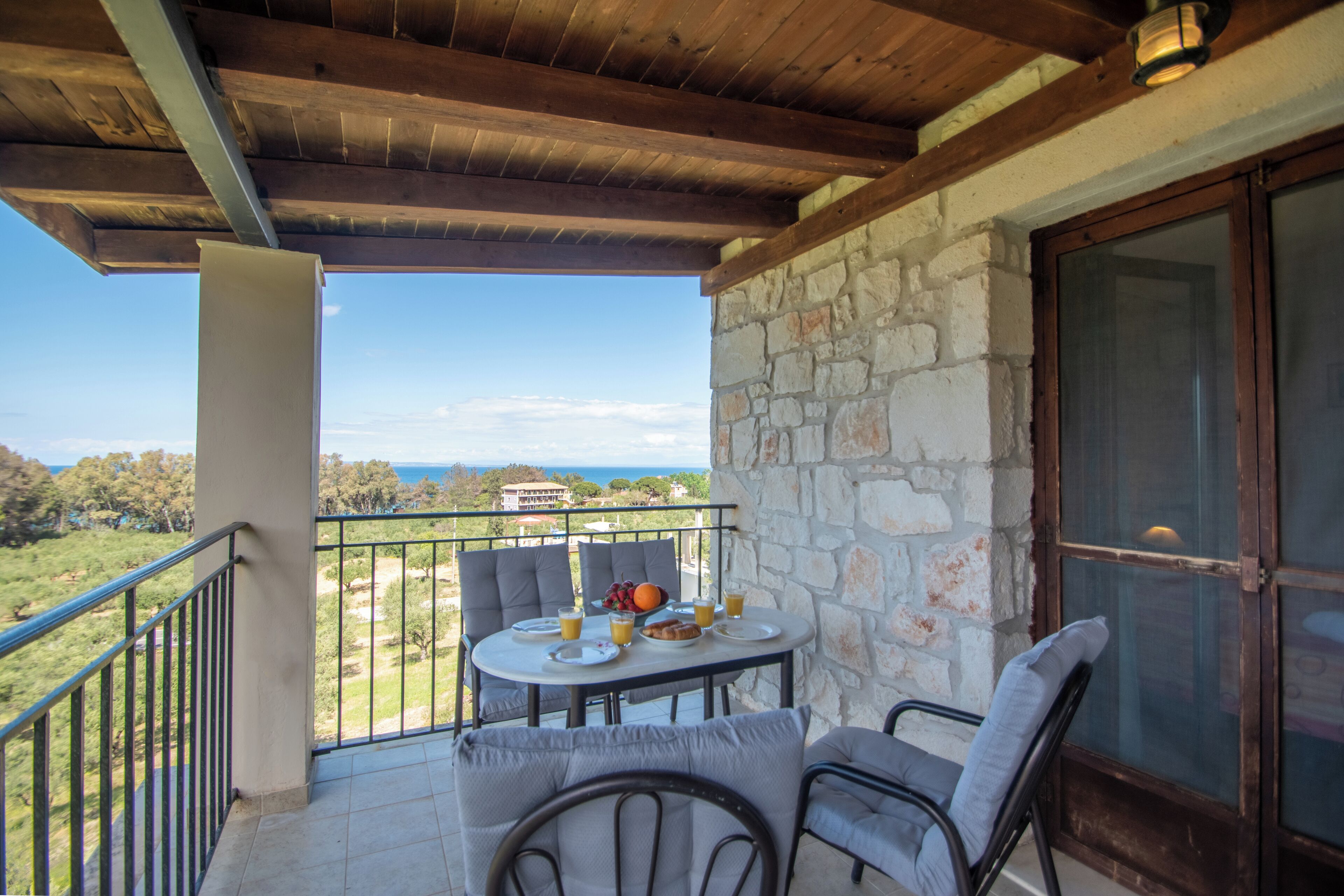 A balcony with a table set for breakfast, overlooking a scenic landscape.