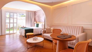 A hotel room with a bed, a sofa, a round wooden table, and a chair. - Santé Vivre L'Experience Livá OFICIAL (Búzios)