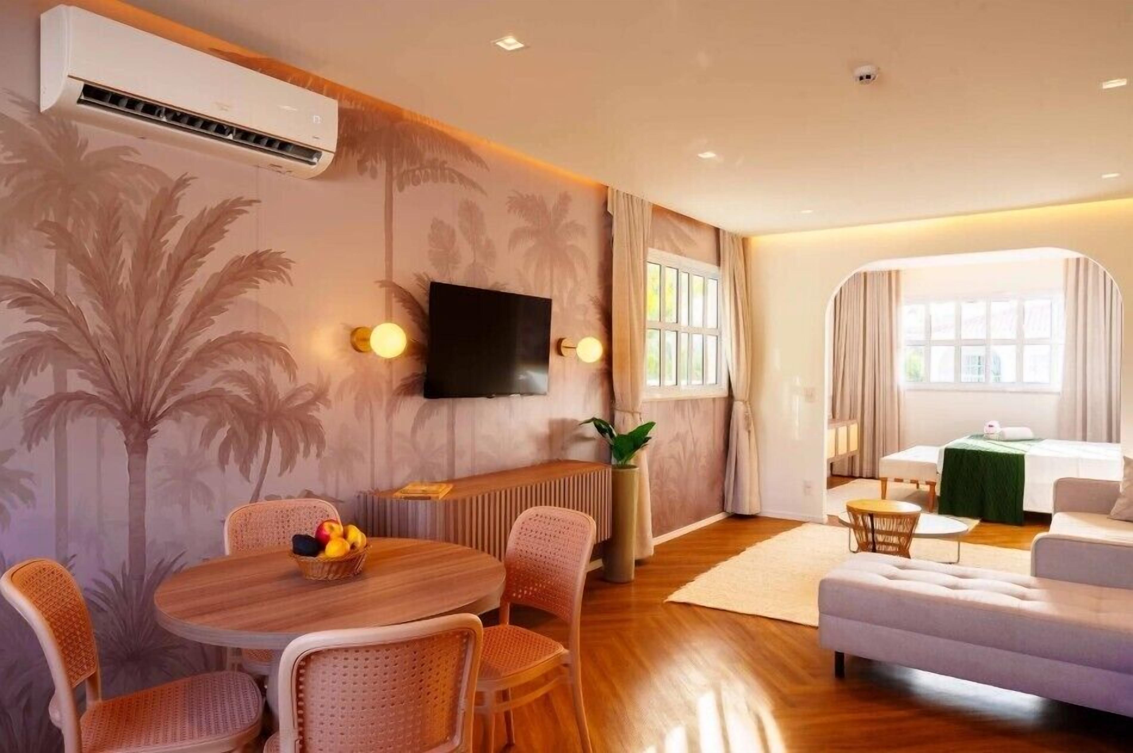 A modern living room with a dining area, a flat-screen TV, and a large window with curtains.