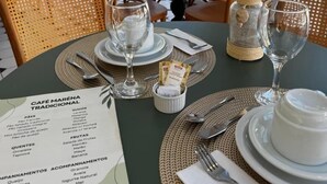 A table set for dining with a menu, glasses, and a decorative plant. - Santé Vivre L'Experience Livá OFICIAL (Búzios)