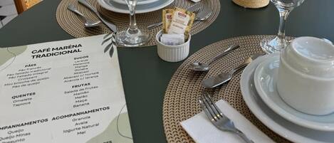 A table set for dining with a menu, glasses, and a vase with dried plants.