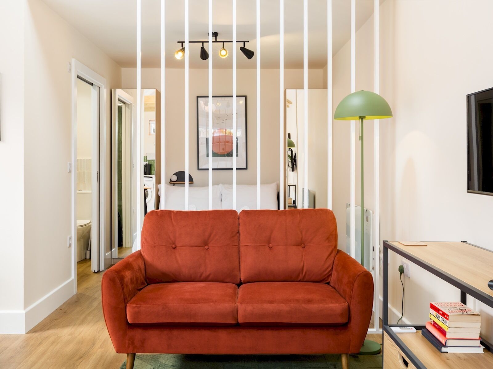 A living room with a red sofa, a green floor lamp, and a bookshelf with books.