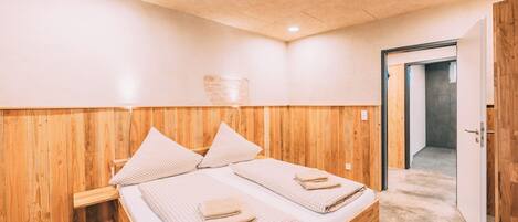 A room with a wooden bed, a wooden headboard, and a door leading to another room.