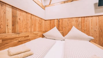 A room with a wooden headboard, two beds with checkered bedding, and a visible cable.