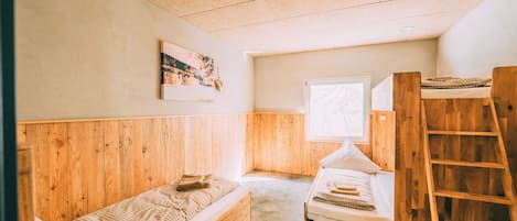 Quarto compacto com duas beliches de madeira, janela com vista e escada de madeira.