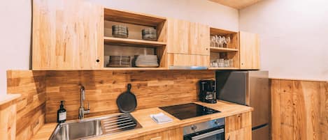 A kitchen with wooden cabinets, a stainless steel sink, a coffee maker, and a built-in oven.