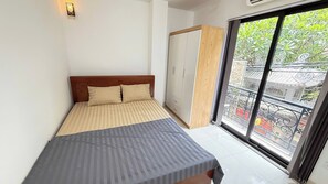 Een slaapkamer met een bed, een kledingkast en een schuifdeur naar een balkon.