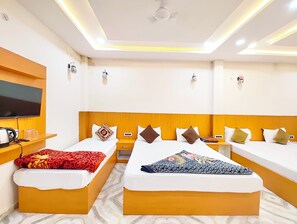 A hotel room with two beds, a TV, a coffee maker, and a small table. - Hotel Nirmala Palace Ayodhya Near Ram Mandir (Faizabad)