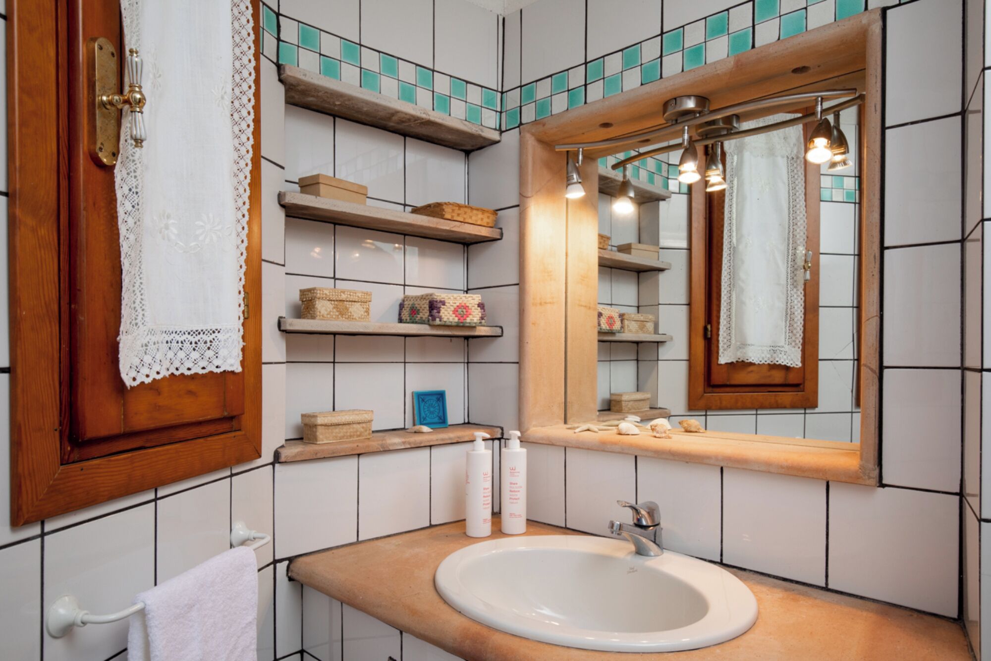 Une salle de bain avec un meuble-lavabo en bois, un lavabo blanc et des étagères remplies de produits de toilette.