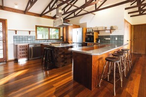 A modern kitchen with a central island, bar stools, and wooden beams on the ceiling. - Mount Panorama Port Douglas Ocean and valley views Tropical Oasis Pool Garden (Port douglas)