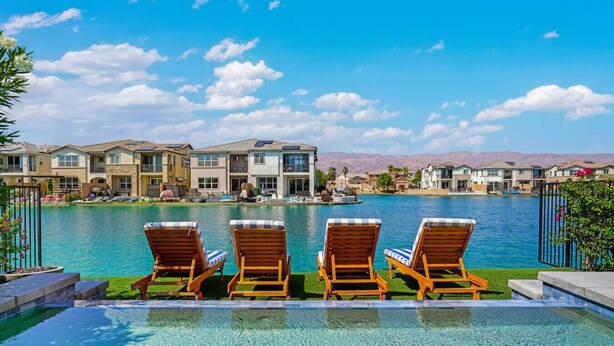 Zona de piscina con tres tumbonas, vista despejada de un complejo residencial y montañas al fondo.