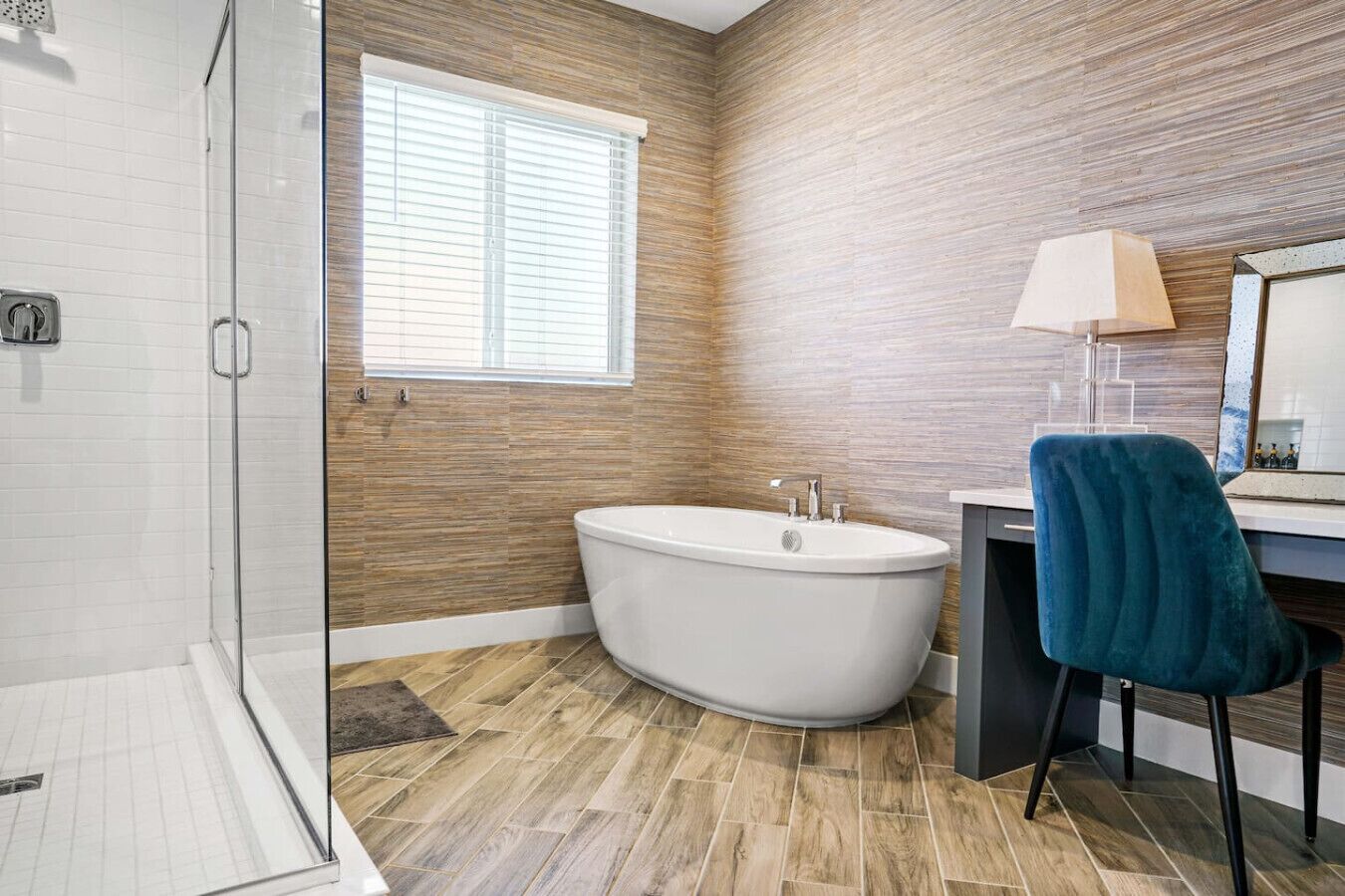 Een moderne badkamer met een vrijstaand bad, een douchecabine met glazen wanden en een houten vloer.