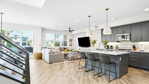 Una cocina moderna con una isla grande, armarios grises y un televisor de pantalla plana.