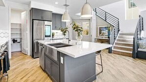 Una cocina moderna con una isla central, electrodomésticos de acero inoxidable e iluminación colgante.